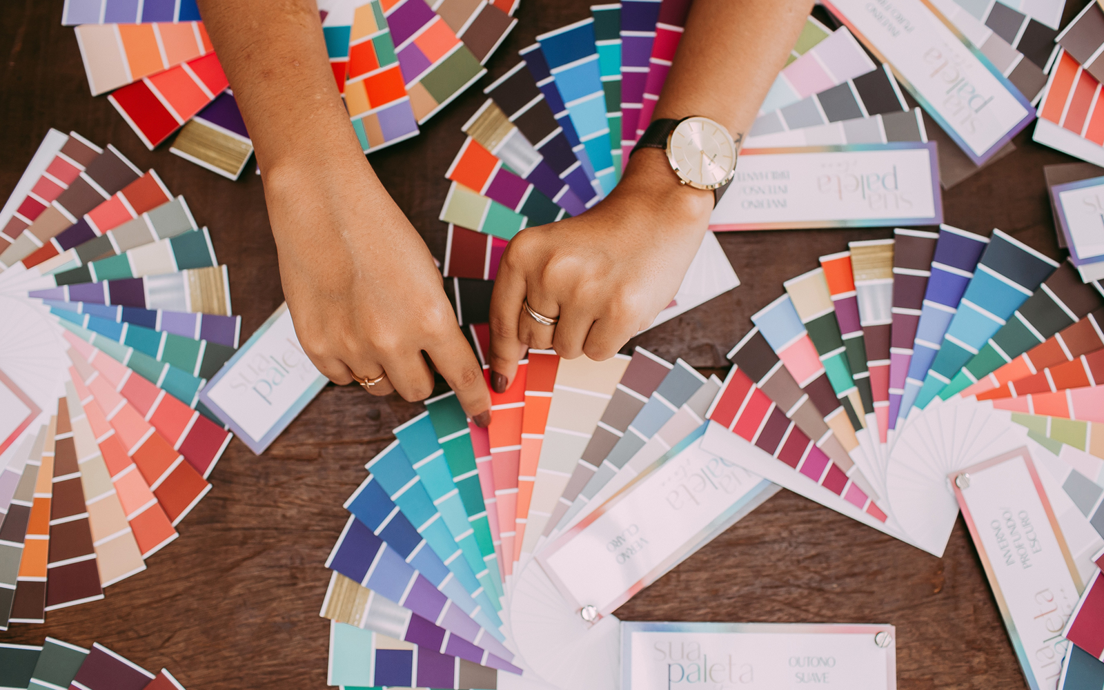 Two hands sorting through different color palettes to establish brand colors.